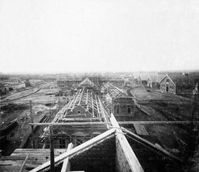 <p>Foto genomen vanaf de nok van het verhoogde middendeel van de linkervleugel van de Van Essenkazerne tijdens de bouw van het complex in 1907-1908. In het midden zijn de (gesloopte) kantinegebouwen in aanbouw te zien, met daarachter zicht op de Arthur Koolkazerne (www.jeoudekazernenu.nl). </p>
